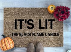 it's lit the black flame candle door mat with flowers and pumpkins next to it