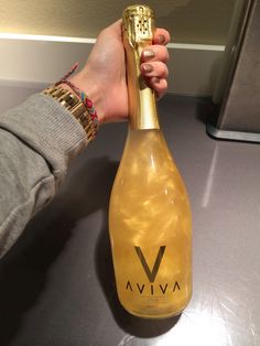 a person holding a bottle of wine in their hand with a gold wrapper around it