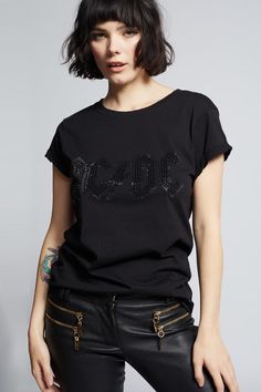 Step into the spotlight in this glittering AC/DC tee. The sleek design features the band's most iconic logo in stunning black crystals that will make you shine like a rock star. Our feminine fitted tee is made with soft cotton fabric, distressed hems, a ribbed crew neckline, and cuffed short sleeves. The design of this style is fitted. For a more standard fit, choose a size up. Details Style #200001 Color: Black Black Crystal AC/DC Logo Fitted T-Shirt Keyword: ACDC 100% Cotton Care/Import Machin Black Embellished Cotton T-shirt, Embellished T-shirt For Night Out, Graphic Cotton T-shirt For Night Out, Black Rhinestone T-shirt For Streetwear, Band Logo T-shirt For Concert, Edgy Cotton T-shirt For Night Out, Rhinestone Embellished Short Sleeve T-shirt For Night Out, Black Cotton T-shirt With Rhinestones, Fitted Cotton Rock T-shirt