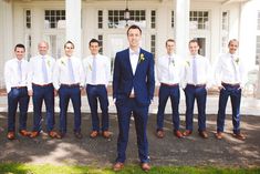 a man standing in front of a group of men wearing blue suits and white shirts