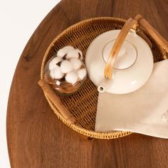 a bowl with cotton balls in it sitting on a table next to a tea pot