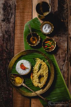 a plate with rice, sauces and other food items on top of a wooden table