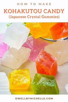 colorful gummy bears sitting on top of a table next to a glass bowl filled with jelly