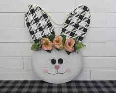 a white vase with flowers in it and a bunny's head on the wall