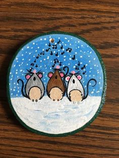 three mice are sitting in the snow under a blue and white glass ornament