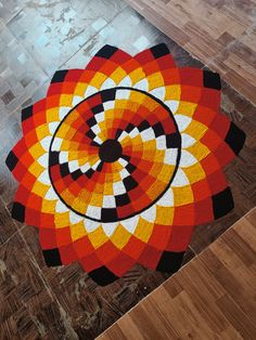 an orange, yellow and black circular design rug on the floor in a living room