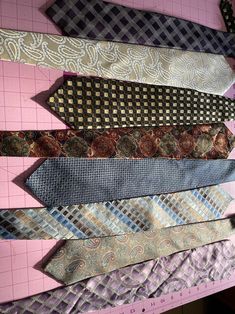 several ties laid out on top of each other next to a pink board with black and white designs