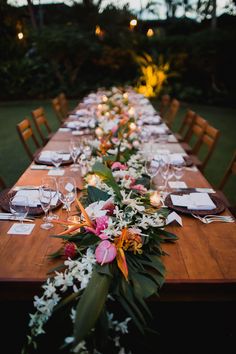 a long table with flowers and candles is set up for an outdoor dinner party in the evening