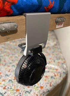 a small fan is attached to the side of a bed