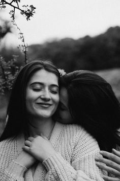 two women are hugging each other outside