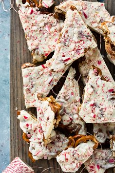 a wooden board topped with candy canes and pretzel cracker pieces covered in white frosting