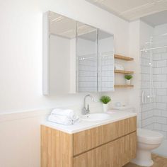 a bathroom with a sink, toilet and shower stall in the corner is white tile