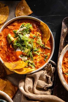 two bowls of chili and tortilla soup with tortillas on the side