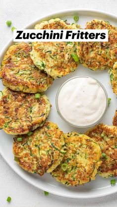 a white plate topped with crab cakes next to a small bowl of ranch dressing on the side