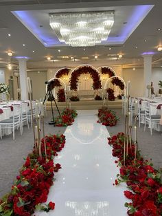 an aisle decorated with red flowers and greenery for a wedding or special event venue