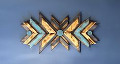 a wooden wall decoration with an arrow shaped design on the front and back side, against a blue background