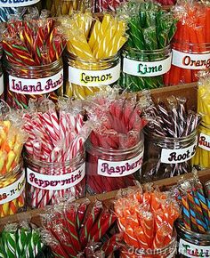 many different colored lollipops are on display in glass jars with name tags