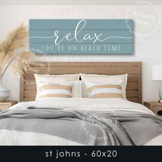 a bed with pillows and blankets in front of a wooden sign that says relax you're on beach time