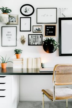 a white desk topped with a wooden chair and lots of framed pictures