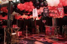 a room filled with red and black balloons, basketball jerseys and other sports memorabilia