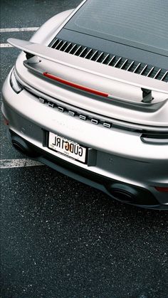 the back end of a silver sports car parked in a parking lot