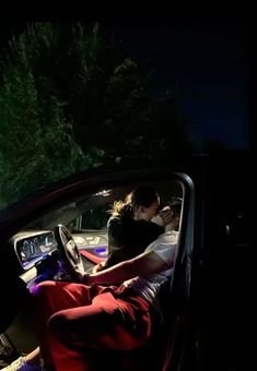 two people sitting in the driver's seat of a car at night