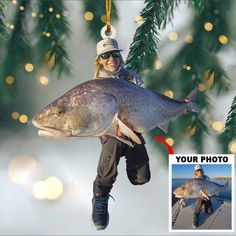 a woman holding a large fish hanging from a christmas tree