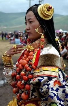 a woman in an elaborately decorated outfit with jewelry and bracelets on her neck