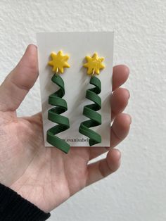 a person holding up two christmas trees made out of green and yellow paper with stars on them