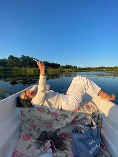 a woman laying on the back of a boat with her hands up in the air