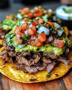 a tortilla topped with meat and vegetables on top of a wooden cutting board