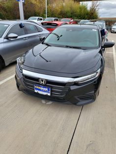 a black car parked in a parking lot next to other cars on the side of the road