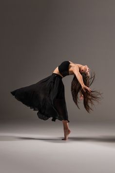 a woman in black dress dancing on grey background