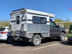 a truck with a camper attached to it parked in a parking lot next to another vehicle