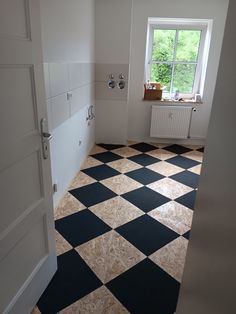 an empty room with black and white checkered flooring on the ground next to a window