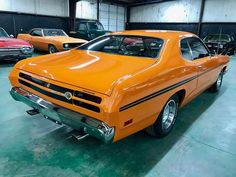 an orange car parked in a garage next to other cars