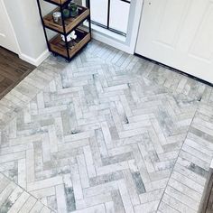 a white door and some shelves on the side of a brick floor in front of a window