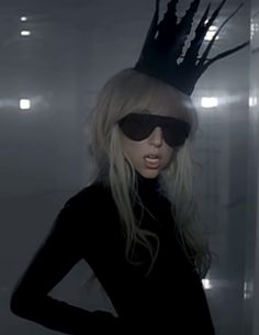 a woman wearing sunglasses and a black dress with a crown on top of her head