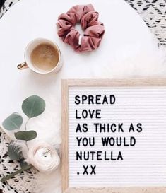 a sign that says spread love as thick as you would nutella xx next to a cup of coffee