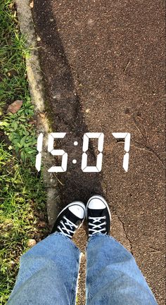 a person standing on the sidewalk with their feet up in front of an electronic clock