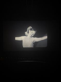 a woman is standing in the dark with her arms spread out and she is wearing a white dress