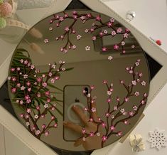 a mirror with pink flowers on it and a person's hand in the reflection