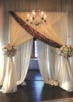 the wedding arch is decorated with flowers and chandelier