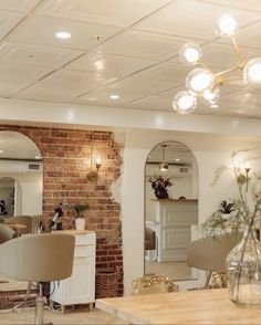 the interior of a salon with chairs, tables and mirrors in front of brick wall