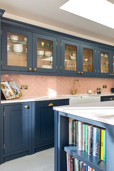 a kitchen with blue cabinets and bookshelves on the counter top, in front of a sink