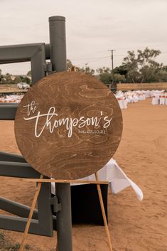 a wooden sign sitting on top of a metal pole next to a white table cloth