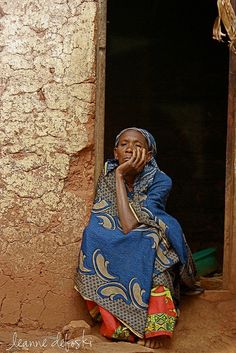 a woman sitting on the ground in front of a door talking on a cell phone