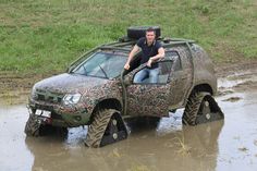 a man is sitting on top of a vehicle in the muddy water with his feet up