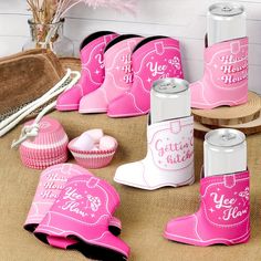 pink cowboy boots and other items are on the floor next to each other, including two cans