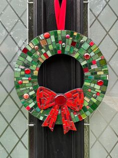 a wreath made out of stained glass with a red bow on the front door handle